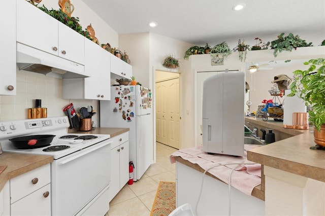 kitchen with light tile patterned flooring, under cabinet range hood, white appliances, white cabinets, and light countertops