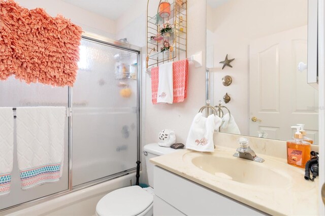 bathroom featuring combined bath / shower with glass door, vanity, and toilet