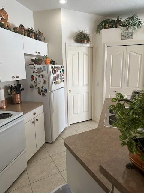 3816 N Cranberry Blvd, North Port, FL 34286 - kitchen with white appliances, light tile patterned floors, white cabinetry, and recessed lighting