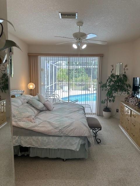 3816 N Cranberry Blvd, North Port, FL 34286 - bedroom with multiple windows, access to exterior, a textured ceiling, carpet flooring, and a ceiling fan
