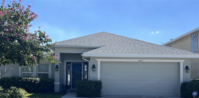 ranch-style house with driveway, a shingled roof, an attached garage, and stucco siding