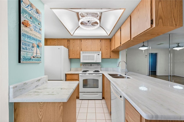 kitchen featuring light tile patterned floors, a peninsula, white appliances, a sink, and light countertops