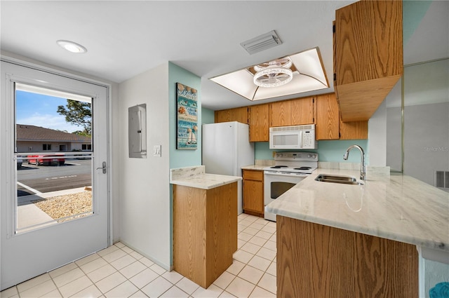 kitchen with white appliances, visible vents, brown cabinets, a peninsula, and a sink