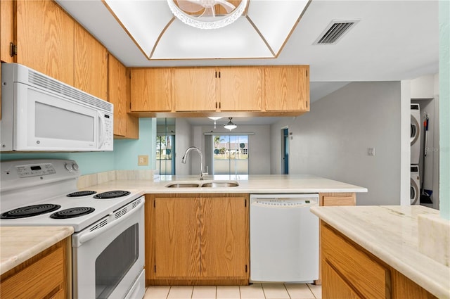 kitchen with light countertops, white appliances, stacked washer / dryer, and a sink