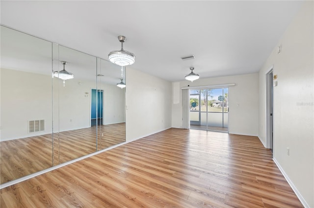 spare room featuring visible vents, baseboards, and wood finished floors