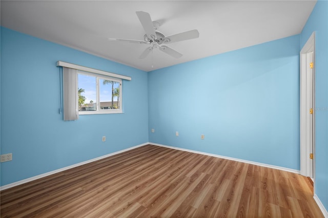 spare room with ceiling fan, light wood finished floors, and baseboards