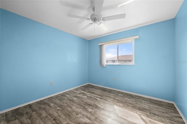 empty room with wood finished floors, a ceiling fan, and baseboards