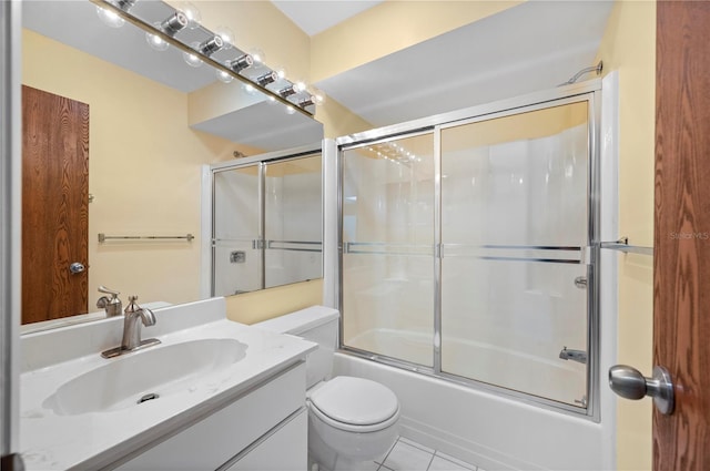 bathroom featuring toilet, bath / shower combo with glass door, vanity, and tile patterned floors