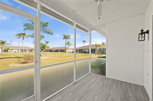 unfurnished sunroom with a residential view and a ceiling fan