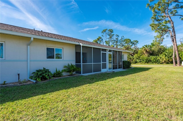 rear view of house featuring a sunroom, a lawn, and stucco siding