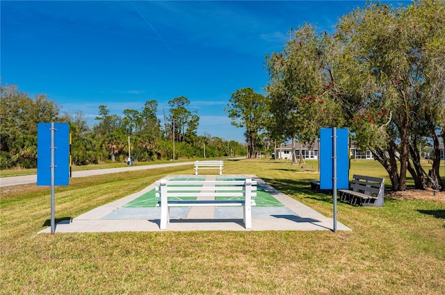 view of property's community featuring shuffleboard and a yard