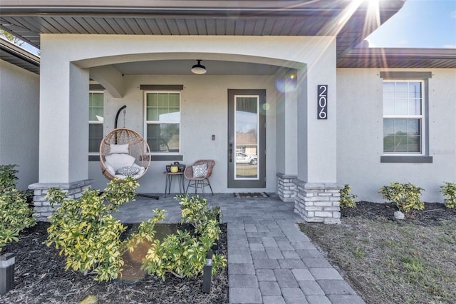 doorway to property featuring a porch and stucco siding