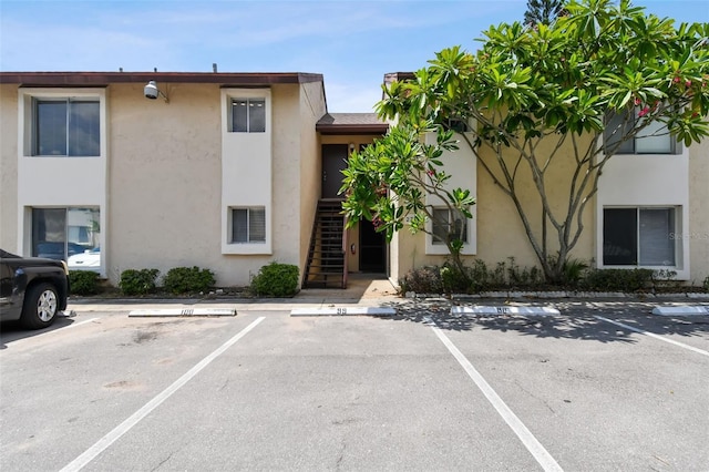 view of property featuring uncovered parking and stairway