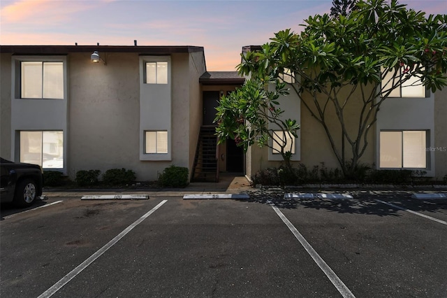 property at dusk featuring uncovered parking and stairway