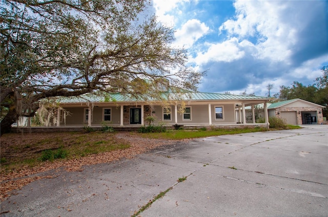 view of front of home featuring a garage, metal roof, a porch, and a standing seam roof