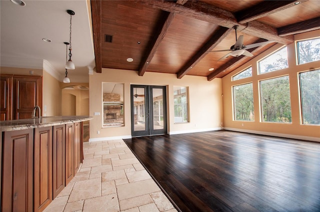 unfurnished living room featuring vaulted ceiling with beams, wooden ceiling, baseboards, and french doors