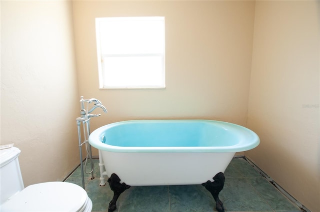 full bathroom featuring a freestanding bath, tile patterned flooring, and toilet