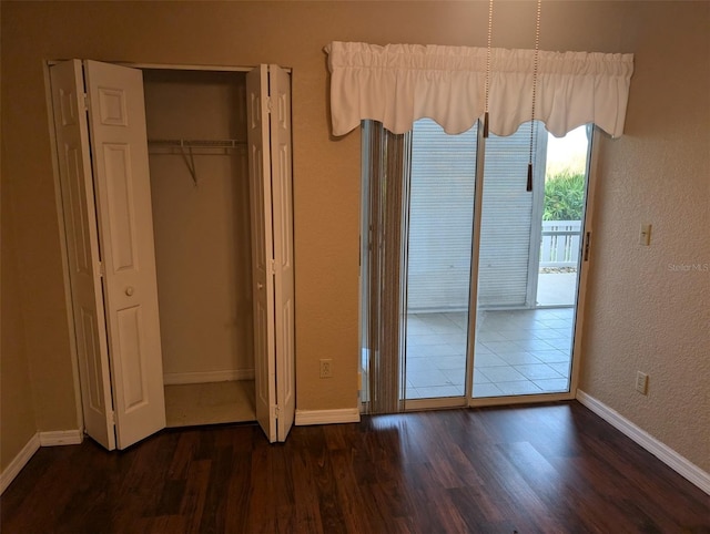 unfurnished bedroom with access to outside, wood finished floors, and baseboards