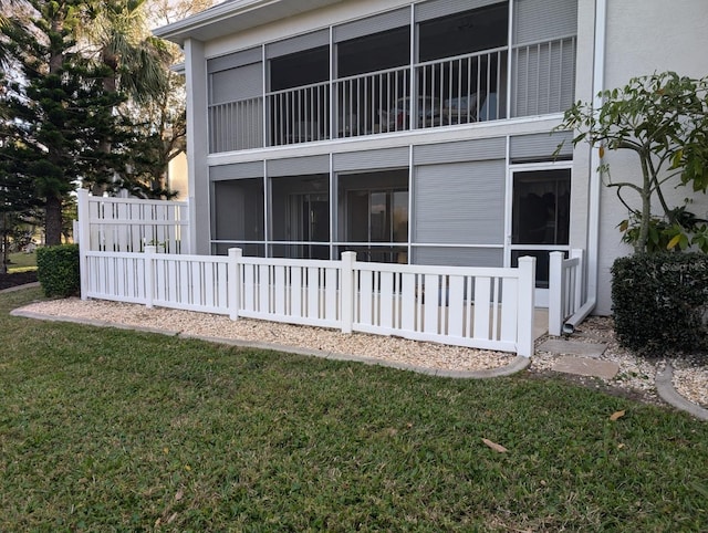 rear view of house with a balcony, a sunroom, and a yard