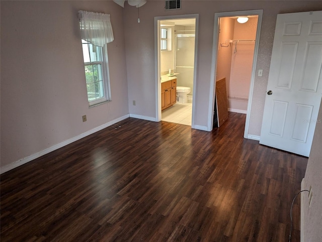 unfurnished bedroom featuring baseboards, visible vents, wood finished floors, a spacious closet, and a closet