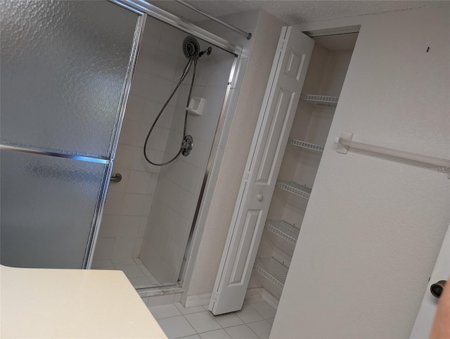 bathroom featuring a shower stall, a textured ceiling, and tile patterned floors