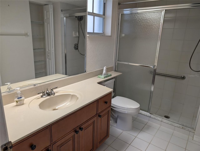 bathroom featuring a textured wall, toilet, tile patterned flooring, vanity, and a shower stall