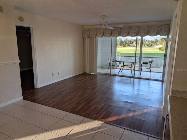 tiled spare room featuring baseboards, visible vents, a textured wall, ceiling fan, and a textured ceiling