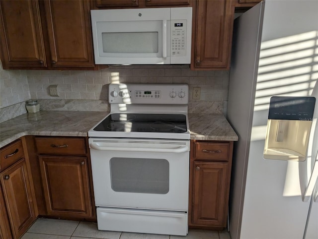 kitchen with white appliances, brown cabinetry, and tasteful backsplash