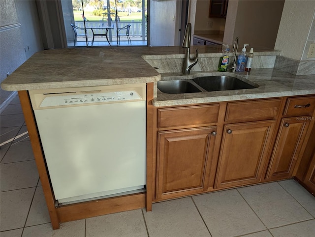 kitchen with a sink, light tile patterned floors, brown cabinets, and dishwasher