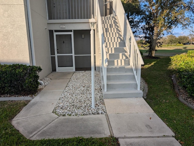 doorway to property with a lawn and stucco siding