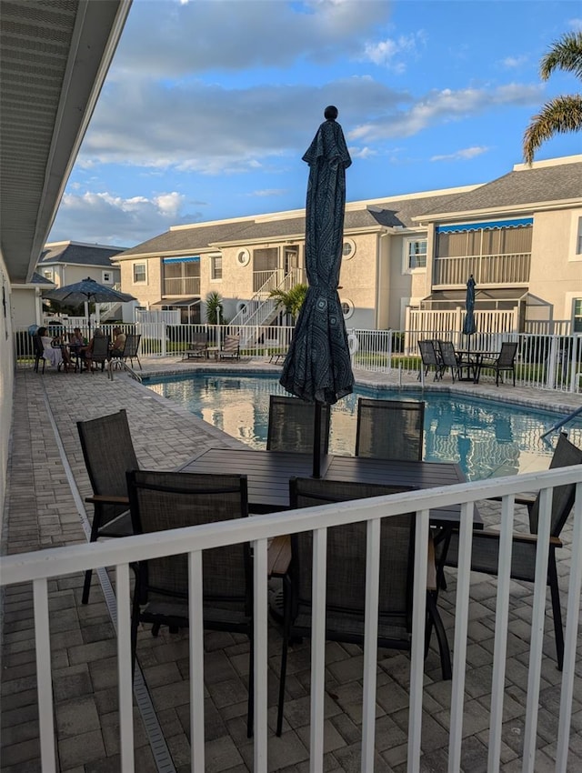 pool with a residential view, a patio area, and fence