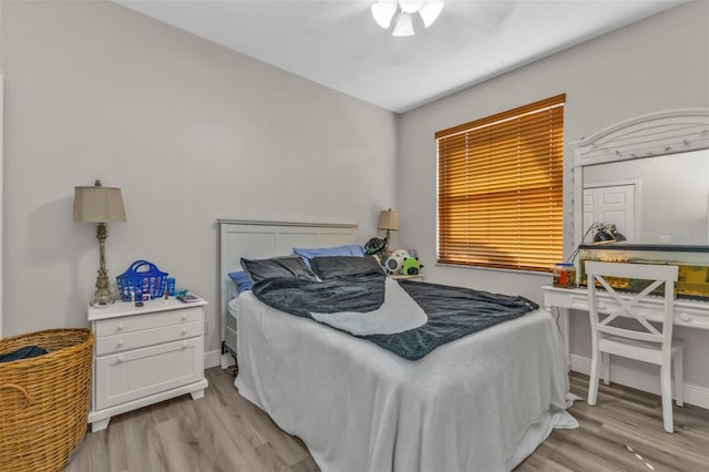 bedroom with a ceiling fan, baseboards, and light wood finished floors