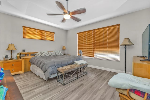 bedroom with ceiling fan, light wood-style flooring, and baseboards