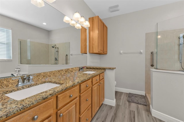 full bathroom with a walk in shower, double vanity, wood finished floors, and a sink