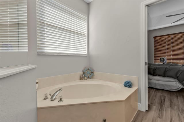 ensuite bathroom featuring wood finished floors, ceiling fan, ensuite bathroom, and a bath