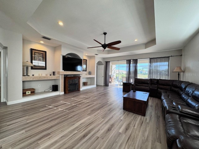 1859 Scarlett Ave, North Port, FL 34289 - living area with a raised ceiling, wood finished floors, a ceiling fan, arched walkways, and a fireplace