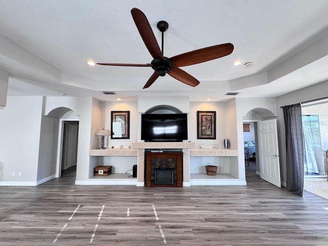 1859 Scarlett Ave, North Port, FL 34289 - unfurnished living room featuring arched walkways, a ceiling fan, wood finished floors, recessed lighting, and a fireplace