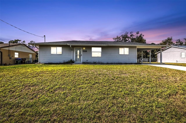 ranch-style home featuring a lawn, a carport, and concrete driveway