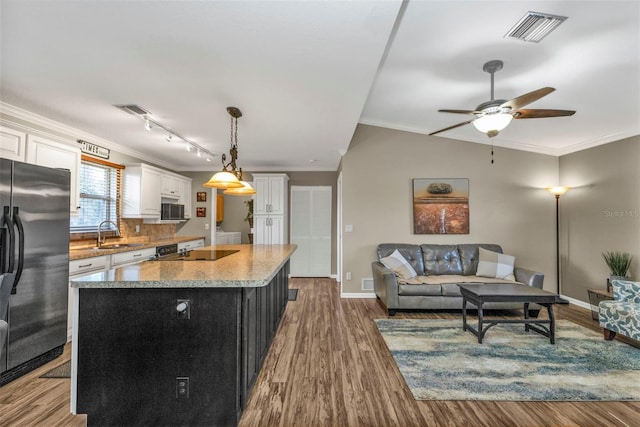 kitchen with a center island, decorative light fixtures, visible vents, white cabinets, and black appliances