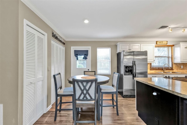 dining space with plenty of natural light, visible vents, ornamental molding, and light wood-style flooring