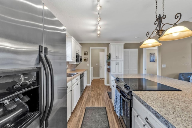 kitchen featuring white cabinets, dark wood-style floors, ornamental molding, stainless steel appliances, and pendant lighting