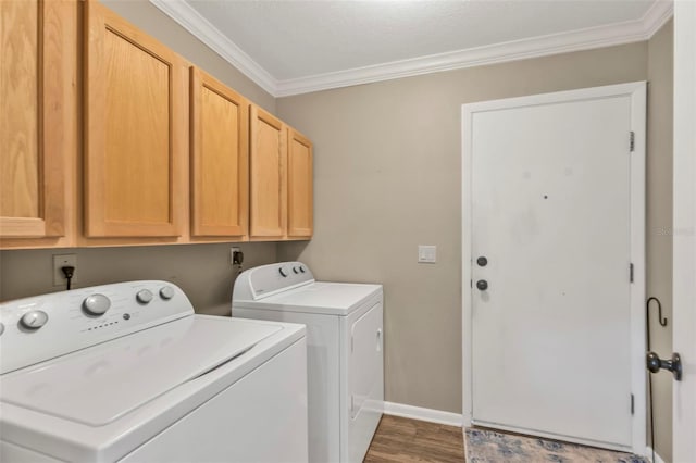 clothes washing area featuring wood finished floors, ornamental molding, washing machine and dryer, and cabinet space