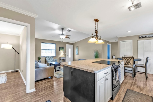 kitchen featuring a center island, range with electric stovetop, light countertops, visible vents, and white cabinets