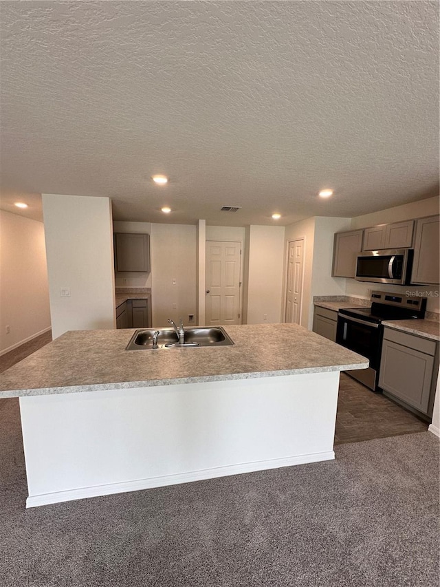 kitchen featuring a kitchen island with sink, stainless steel appliances, a sink, light countertops, and gray cabinets