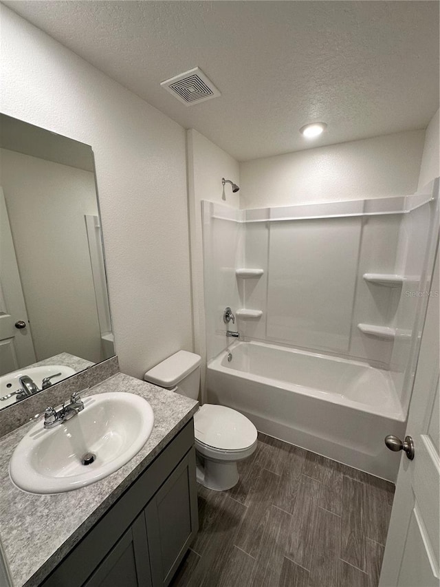 bathroom with bathtub / shower combination, visible vents, toilet, vanity, and a textured ceiling