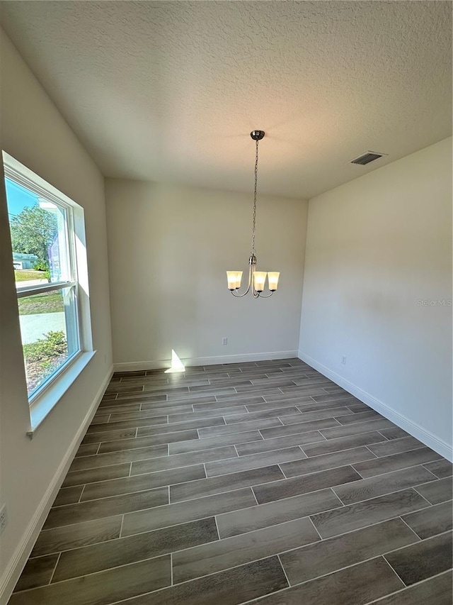 spare room featuring wood tiled floor, visible vents, a notable chandelier, and baseboards