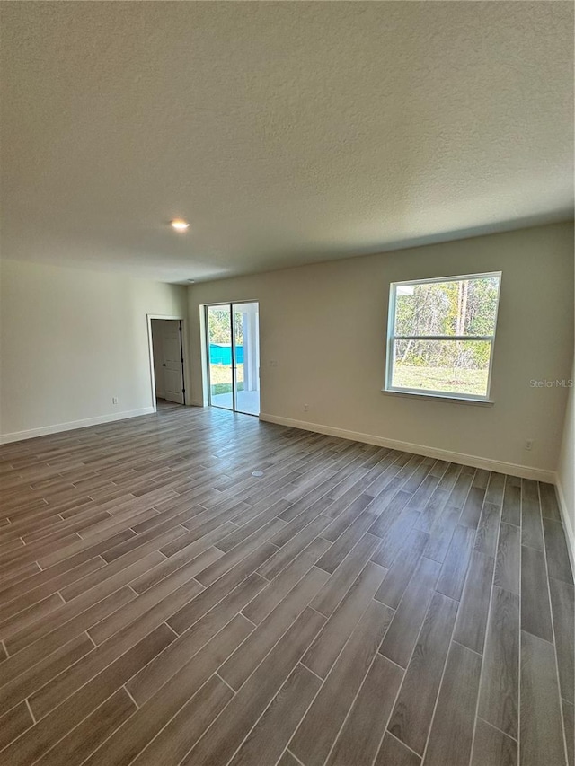 empty room with baseboards, dark wood finished floors, and a textured ceiling