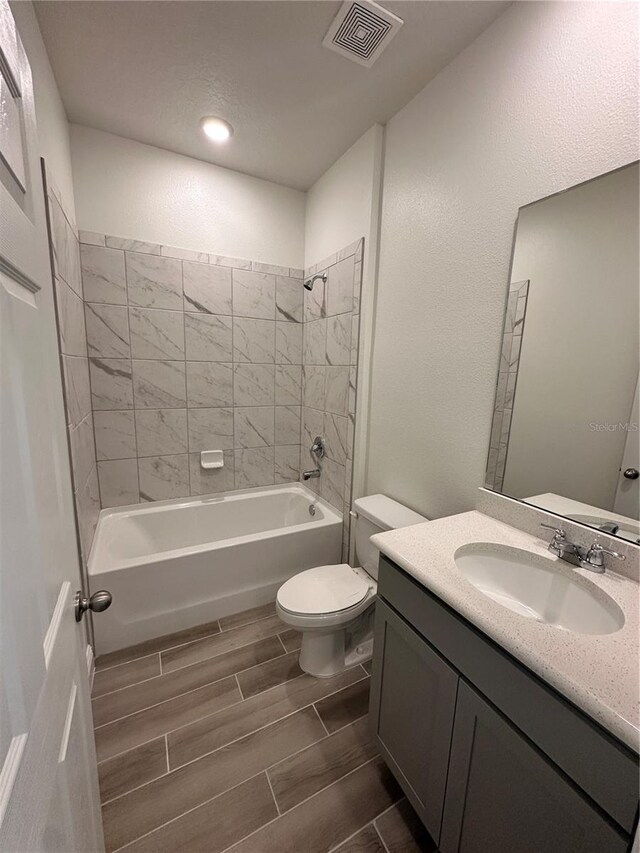 full bathroom with visible vents, toilet, wood tiled floor, tub / shower combination, and vanity