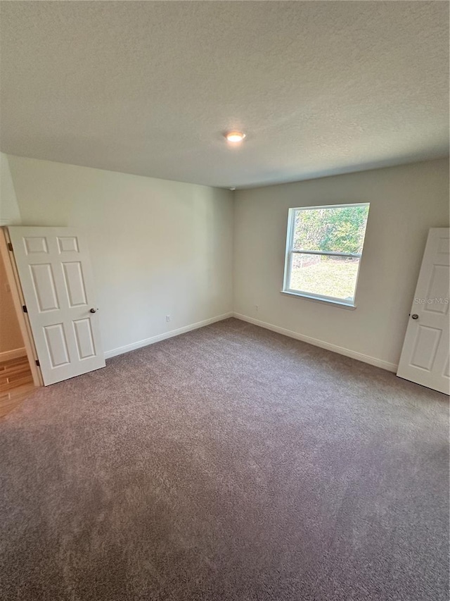 unfurnished bedroom with carpet floors, baseboards, and a textured ceiling