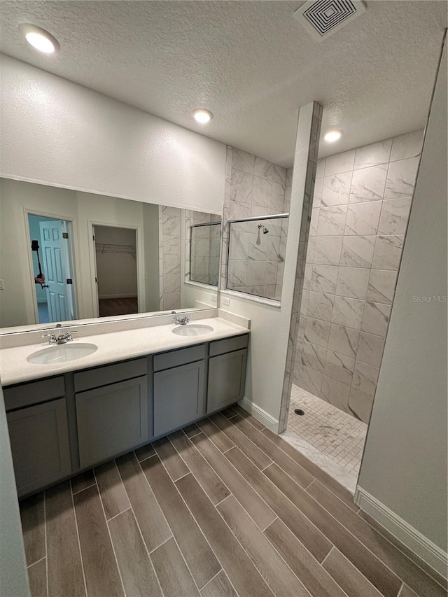 bathroom featuring walk in shower, a sink, visible vents, and wood tiled floor